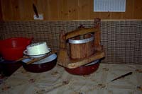 Iz sladkega sira izcedijo sirotko v leseni stiskalnici. Na levi odcejeni kisli sir (T. Cevc, 1996).